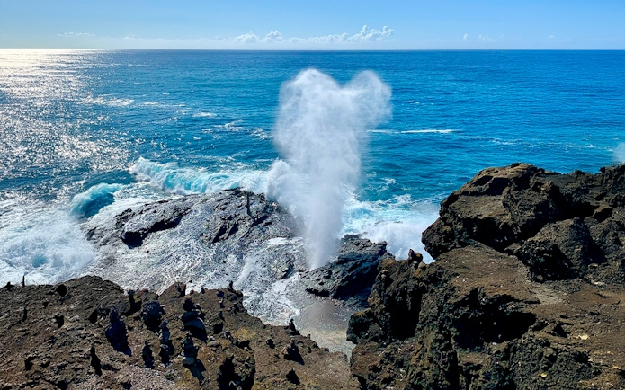 Halona Blowhole spouting water against rocky coastline, Oahu, Hawaii.