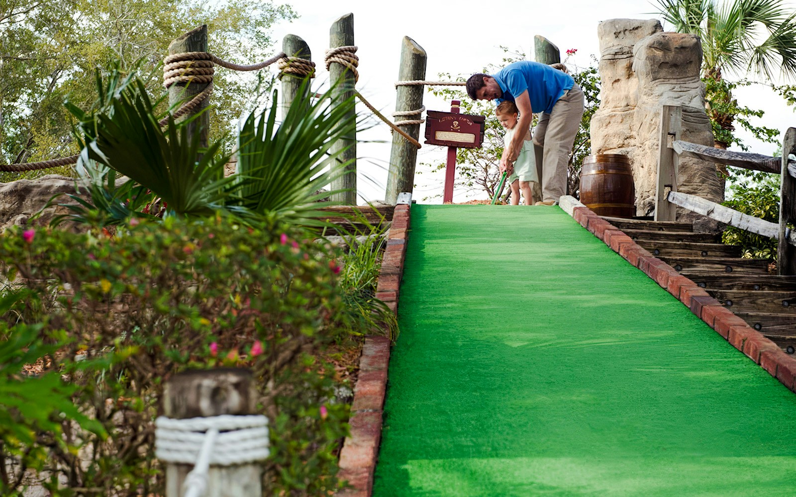 Father and child playing mini-golf at Pirate's Cove Adventure Golf.