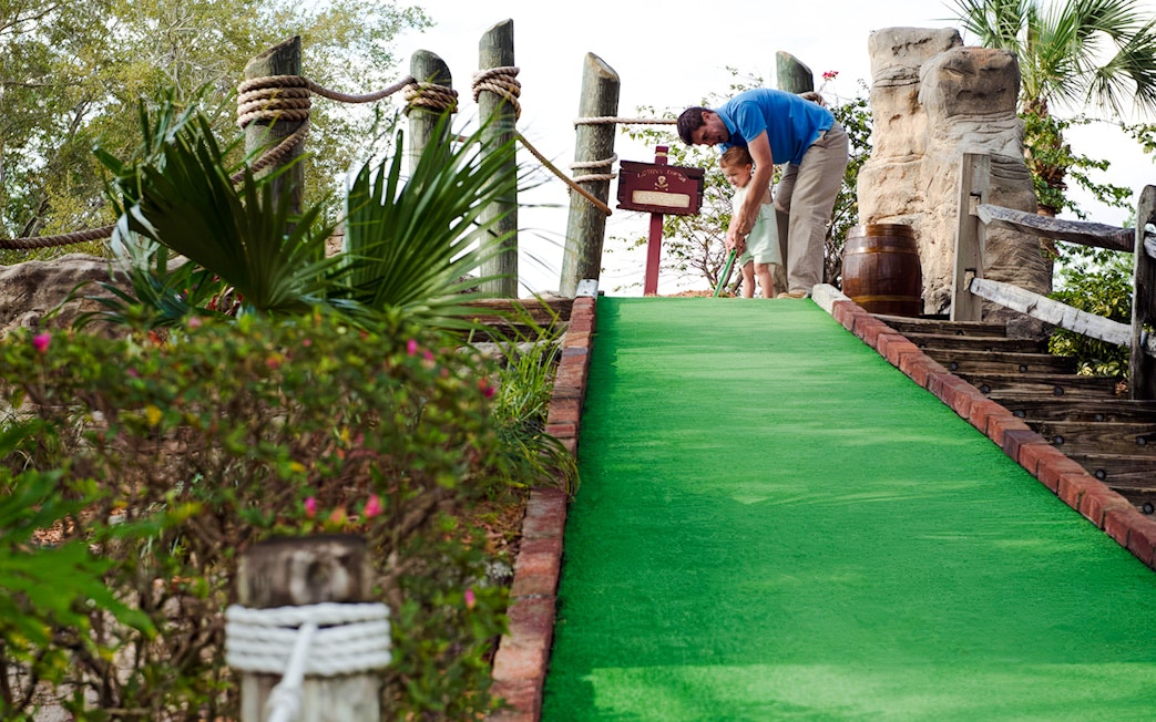 Father and child playing mini-golf at Pirate's Cove Adventure Golf.