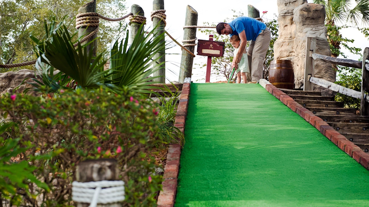 Father and child playing mini-golf at Pirate's Cove Adventure Golf.
