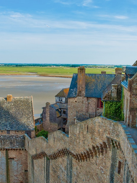 Mont St. Michel stone buildings and walls with tidal flats in the background.