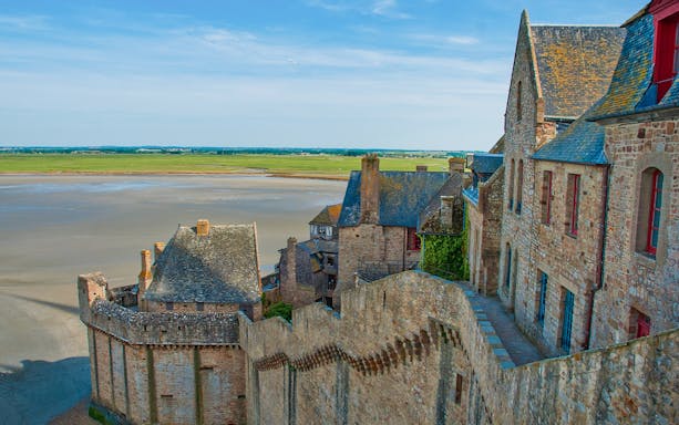 Mont St. Michel stone buildings and walls with tidal flats in the background.