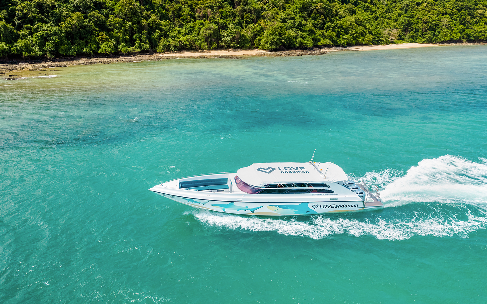 Speed boat cruising towards Similan Island with lush coastline in the background.
