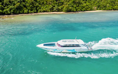 Speed boat cruising towards Similan Island with lush coastline in the background.