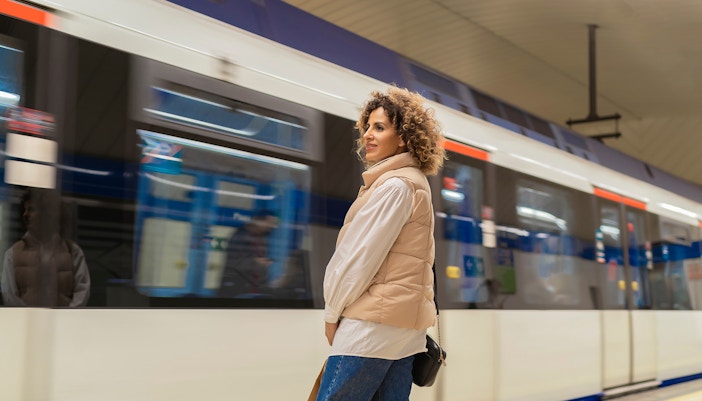 Woman standing on platform as train arrives at Madrid Príncipe Pio station.
