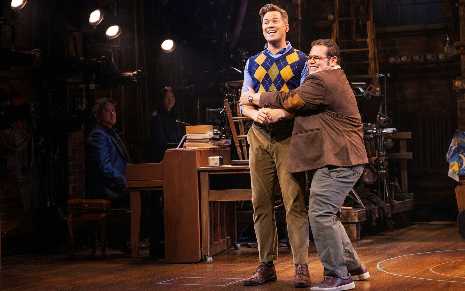 Actors performing a scene from "Gutenberg! The Musical!" on stage with a piano in the background.