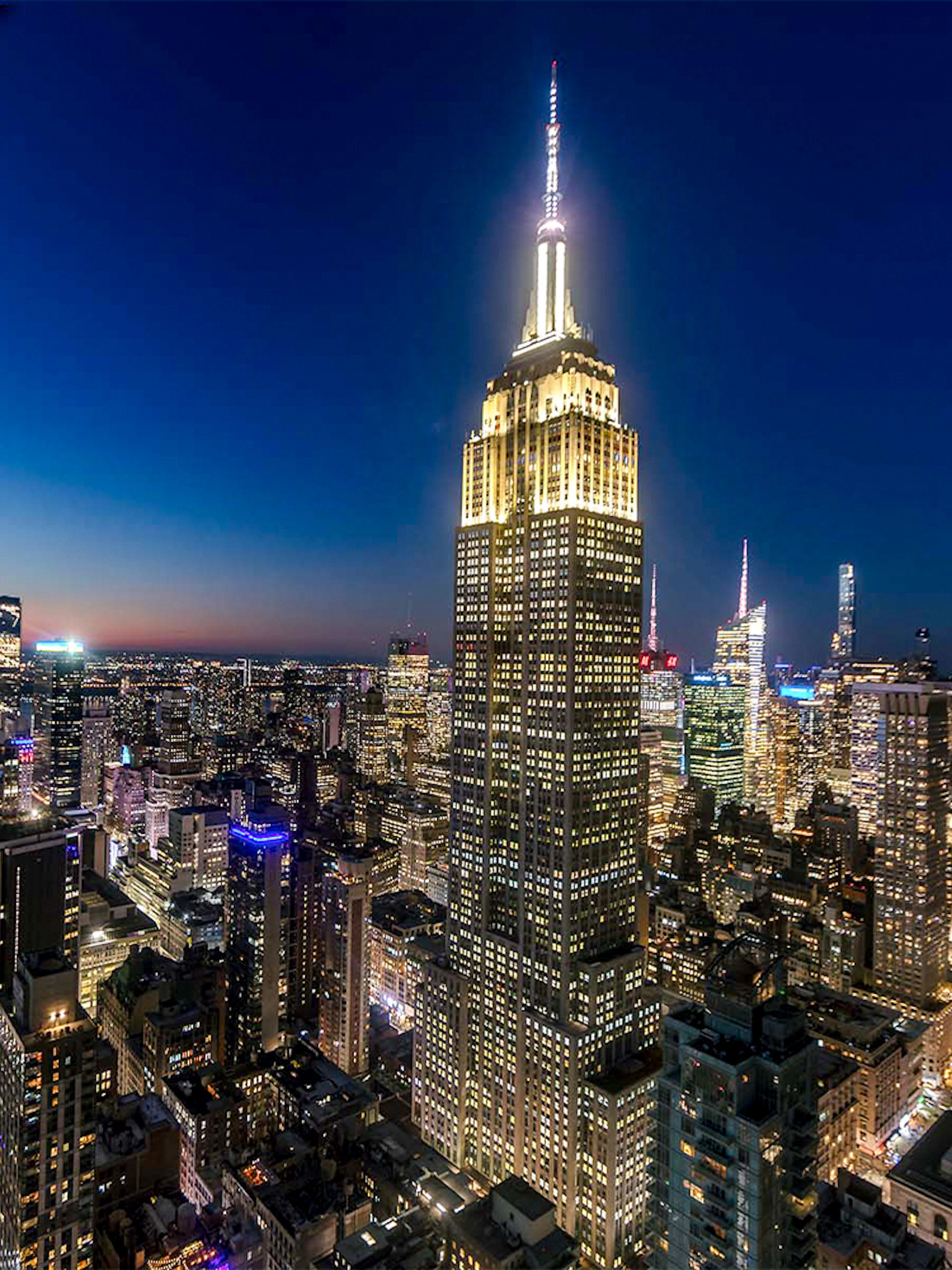 Empire State Building illuminated at night in New York City skyline.