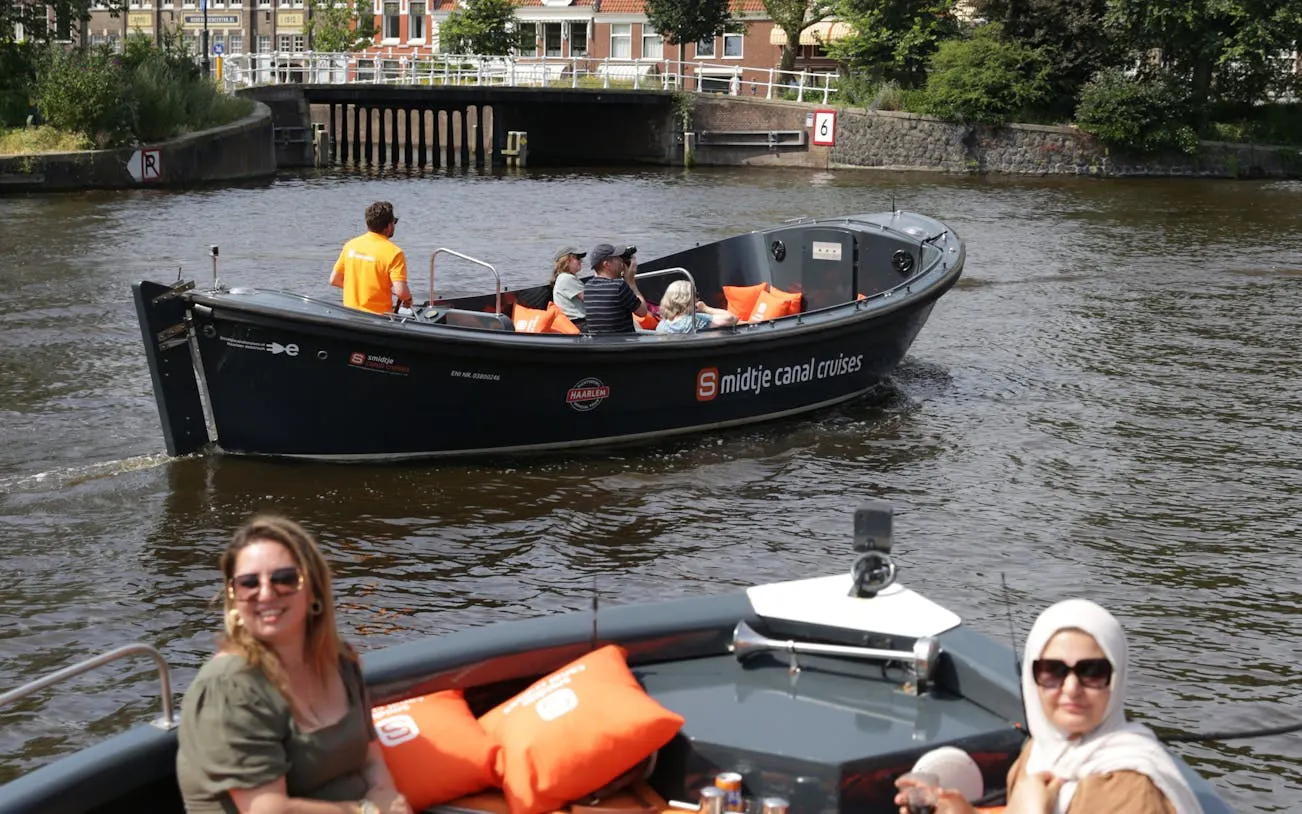 Open boat on Haarlem canal with passengers enjoying live skipper commentary.