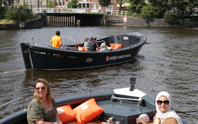 Open boat on Haarlem canal with passengers enjoying live skipper commentary.