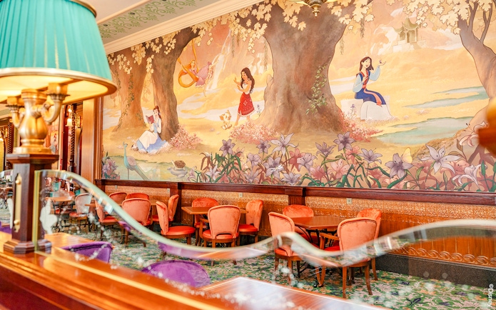Disneyland World of Frozen Adventure restaurant with mural of princesses and elegant seating.