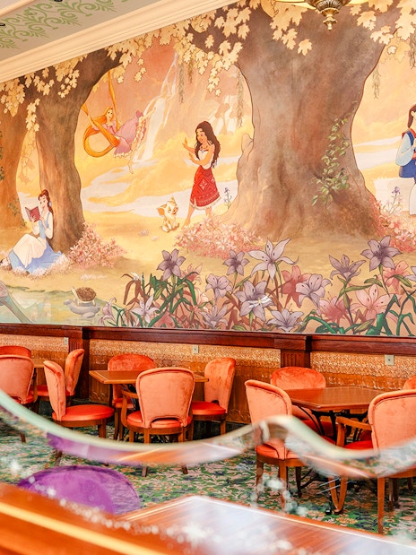 Disneyland World of Frozen Adventure restaurant with mural of princesses and elegant seating.