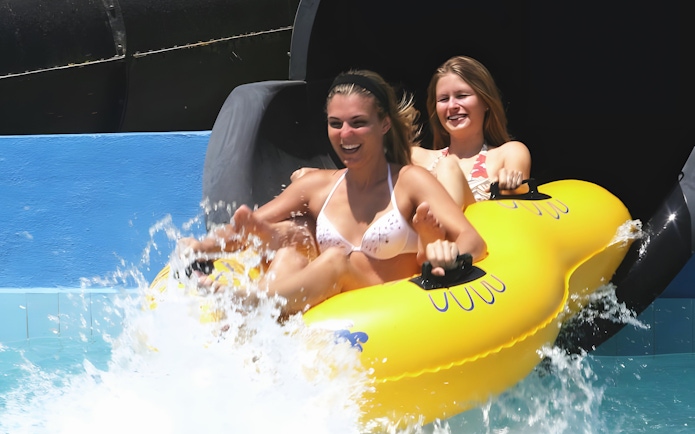 Two people on a yellow raft exiting the Black Hole slide at Aquopolis Cullera.