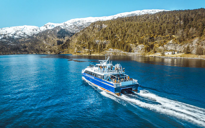 Cruise ship sailing through Mostraumen Fjord with snowy mountains in the background.