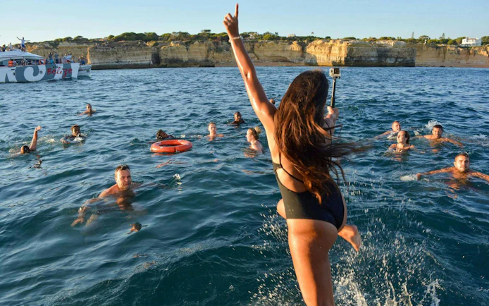 People swimming near a boat during Albufeira sunset sailing tour in Algarve.