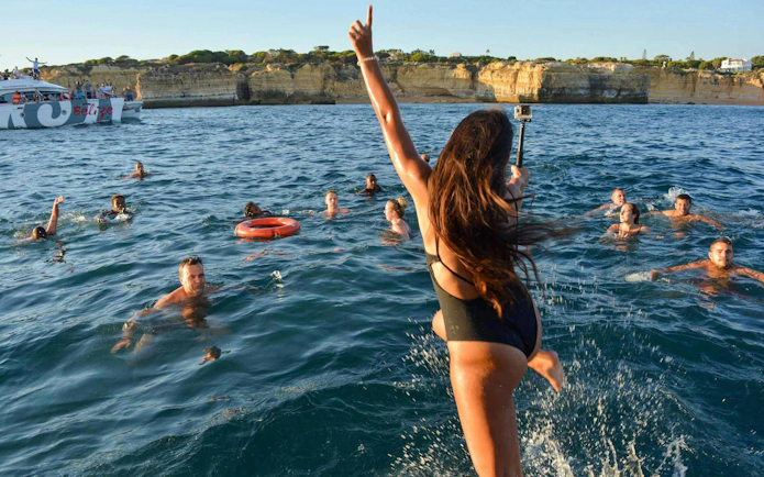 People swimming near a boat during Albufeira sunset sailing tour in Algarve.