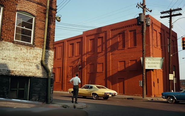 Red brick building with a sign for Methodist Publishing House, viewed from a street corner.
