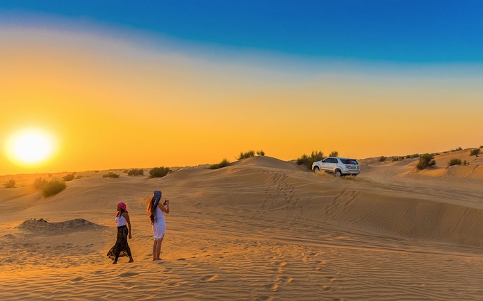 Desert safari with dune bashing and sandboarding in Dubai at sunset.