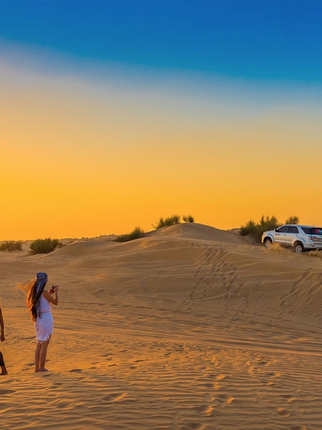 Desert safari with dune bashing and sandboarding in Dubai at sunset.