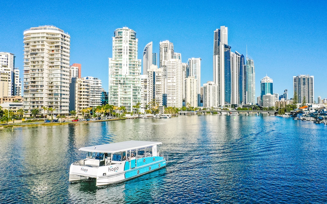 Sightseeing cruise boat on Gold Coast waterway with city skyline in background.