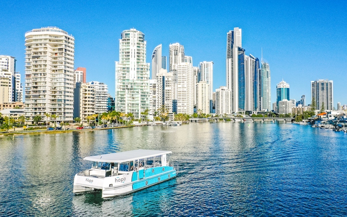 Sightseeing cruise boat on Gold Coast waterway with city skyline in background.