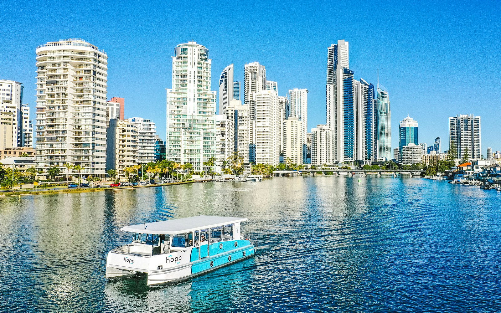 Sightseeing cruise boat on Gold Coast waterway with city skyline in background.