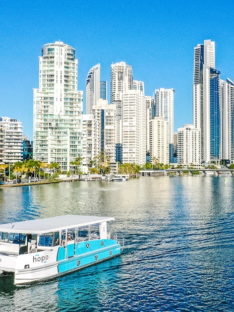 Sightseeing cruise boat on Gold Coast waterway with city skyline in background.