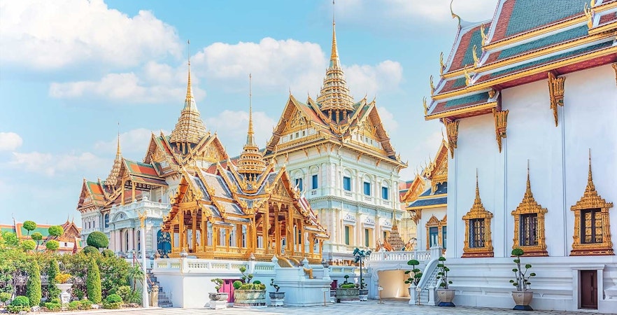 Grand Palace and ornate temples in Bangkok under a clear sky.