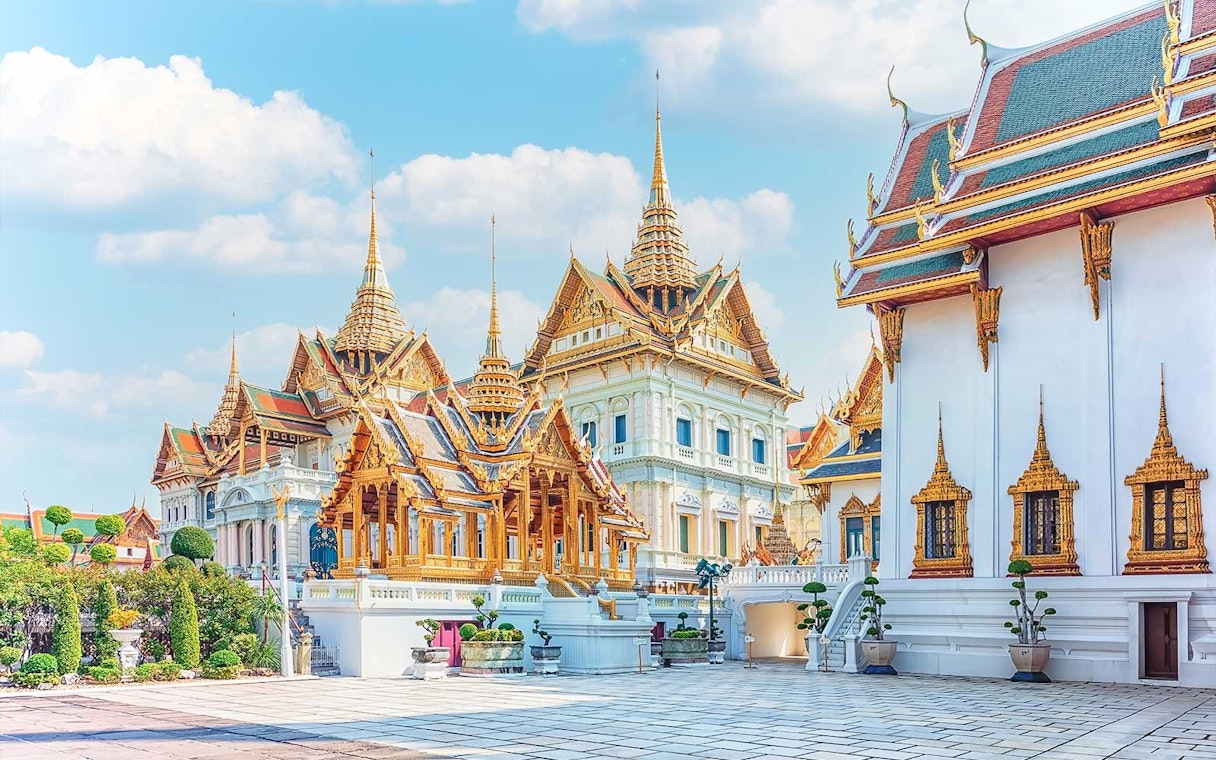 Grand Palace and ornate temples in Bangkok under a clear sky.