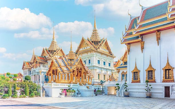 Grand Palace and ornate temples in Bangkok under a clear sky.