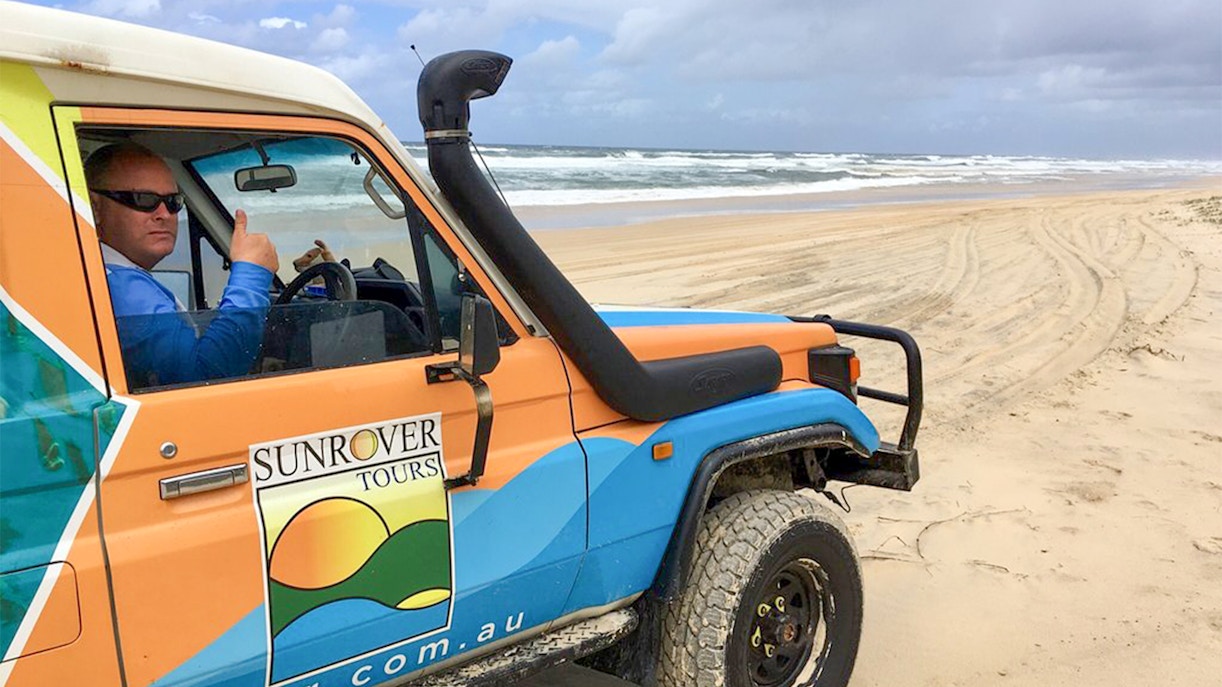 4WD vehicle on Moreton Island beach with Sunrover Tours logo.