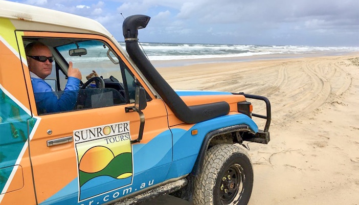 4WD vehicle on Moreton Island beach with Sunrover Tours logo.