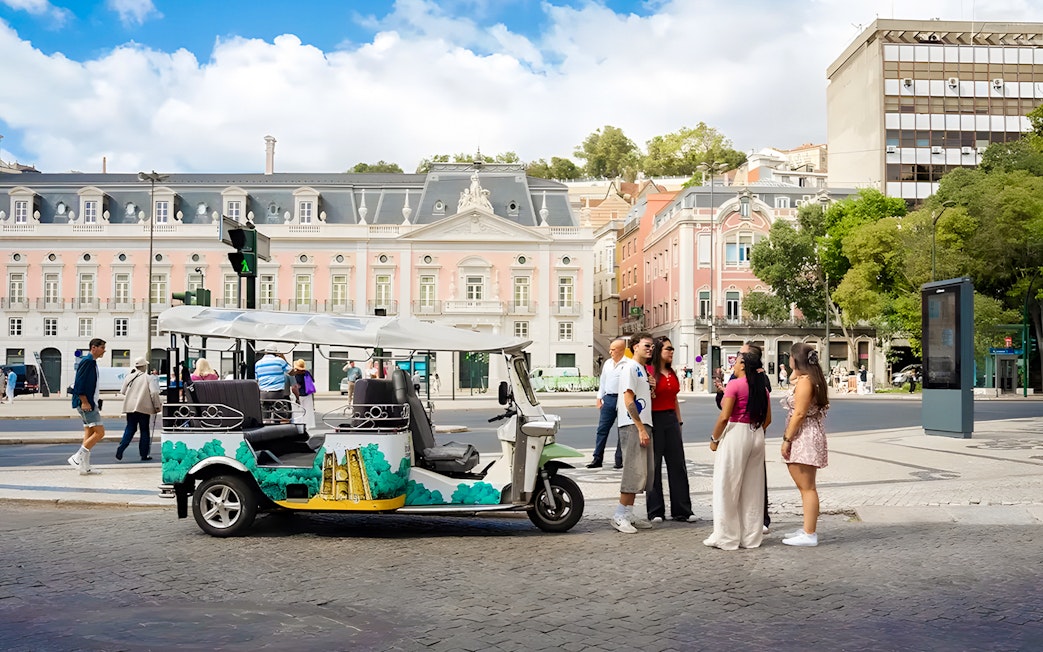 Tourists with guide at scenic Lisbon spot during eco tuk tuk tour.