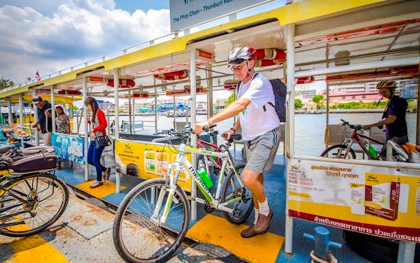 Cyclist boarding a ferry with a bike on a Bangkok guided cycling tour.