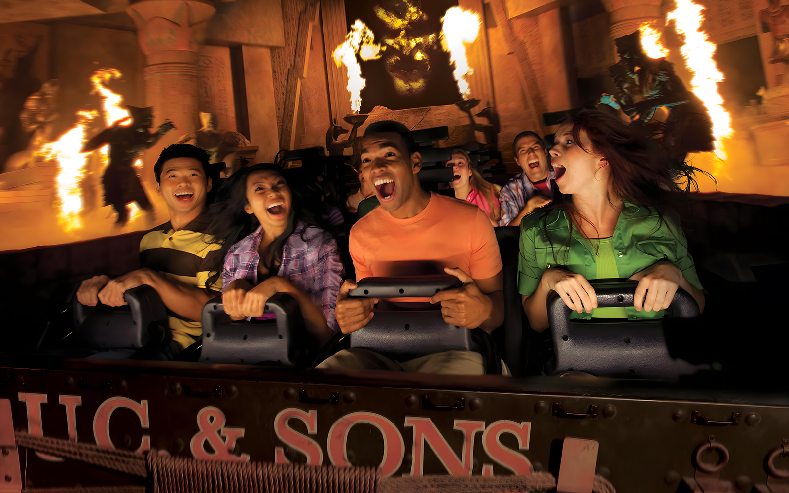 Visitors on a thrilling ride at Universal Studios Hollywood with fire effects in the background.