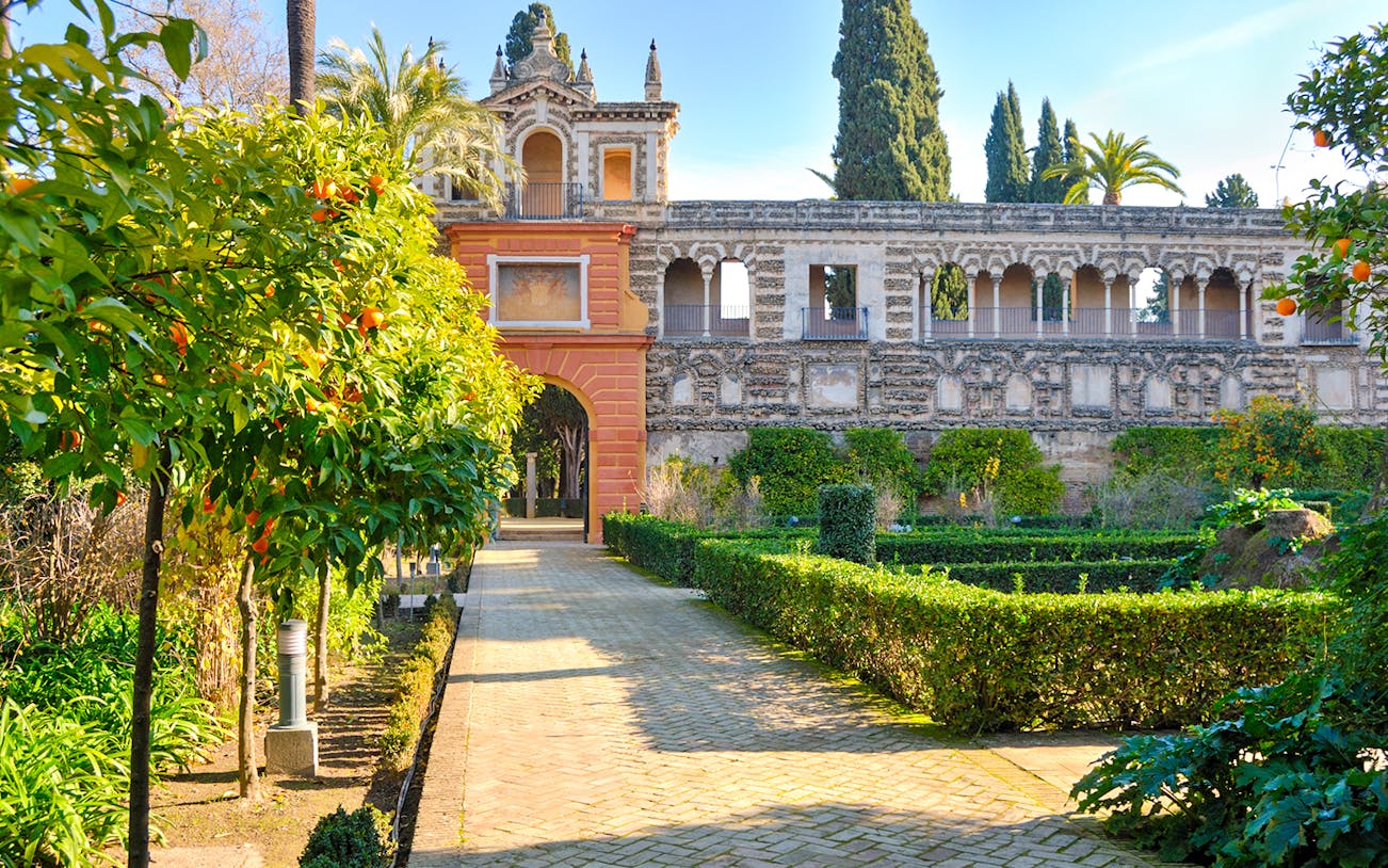 Alcove door in the gardens of Alcazar Seville with orange trees and historic architecture.