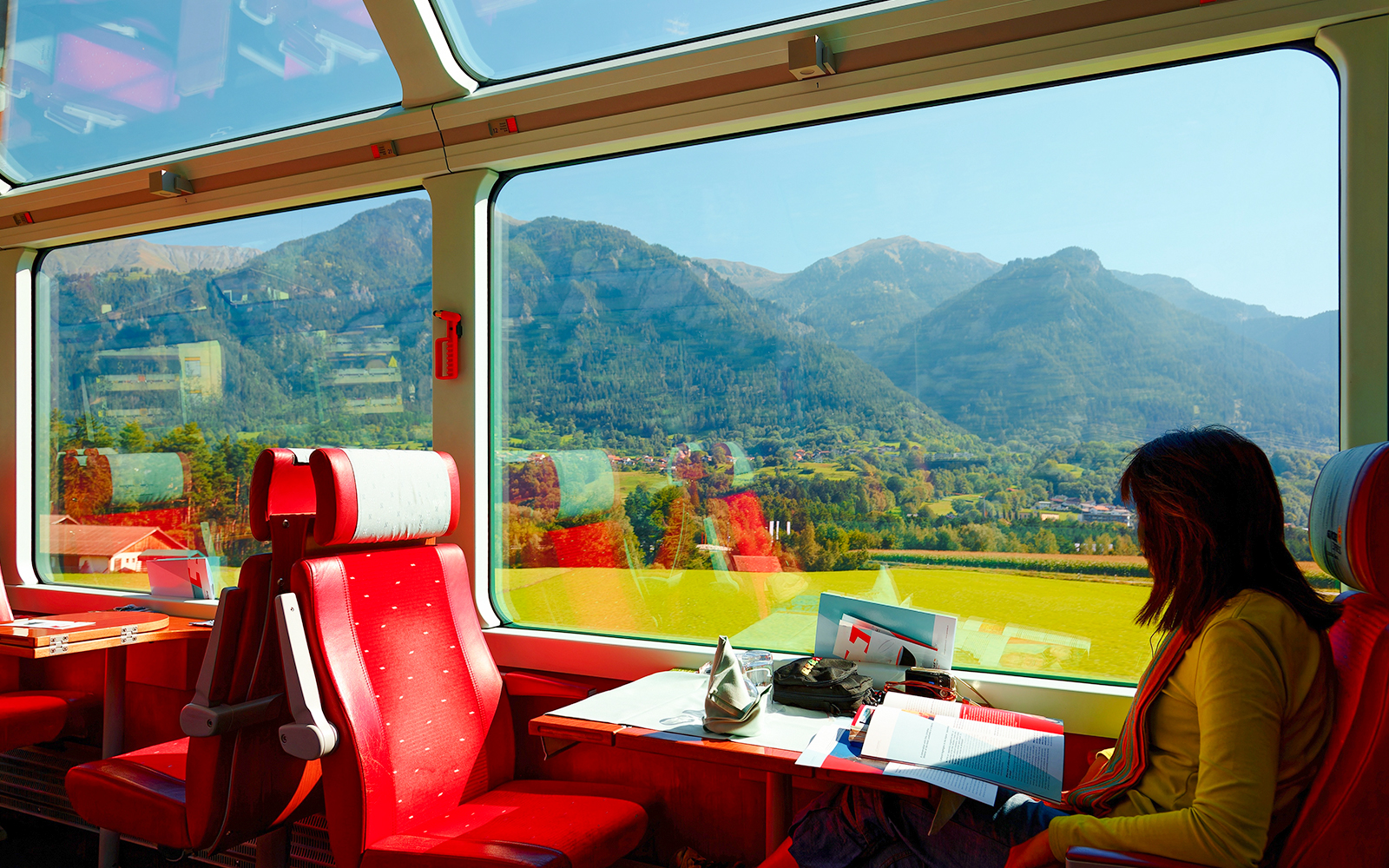 A woman enjoying panoramic mountain views in first class of Glacier Express