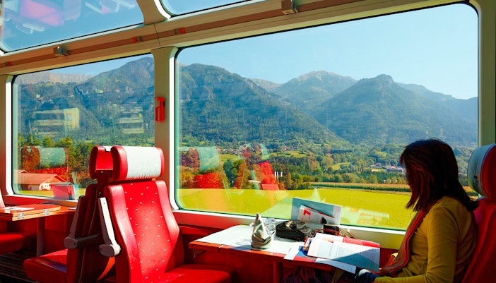 A woman enjoying panoramic mountain views in first class of Glacier Express