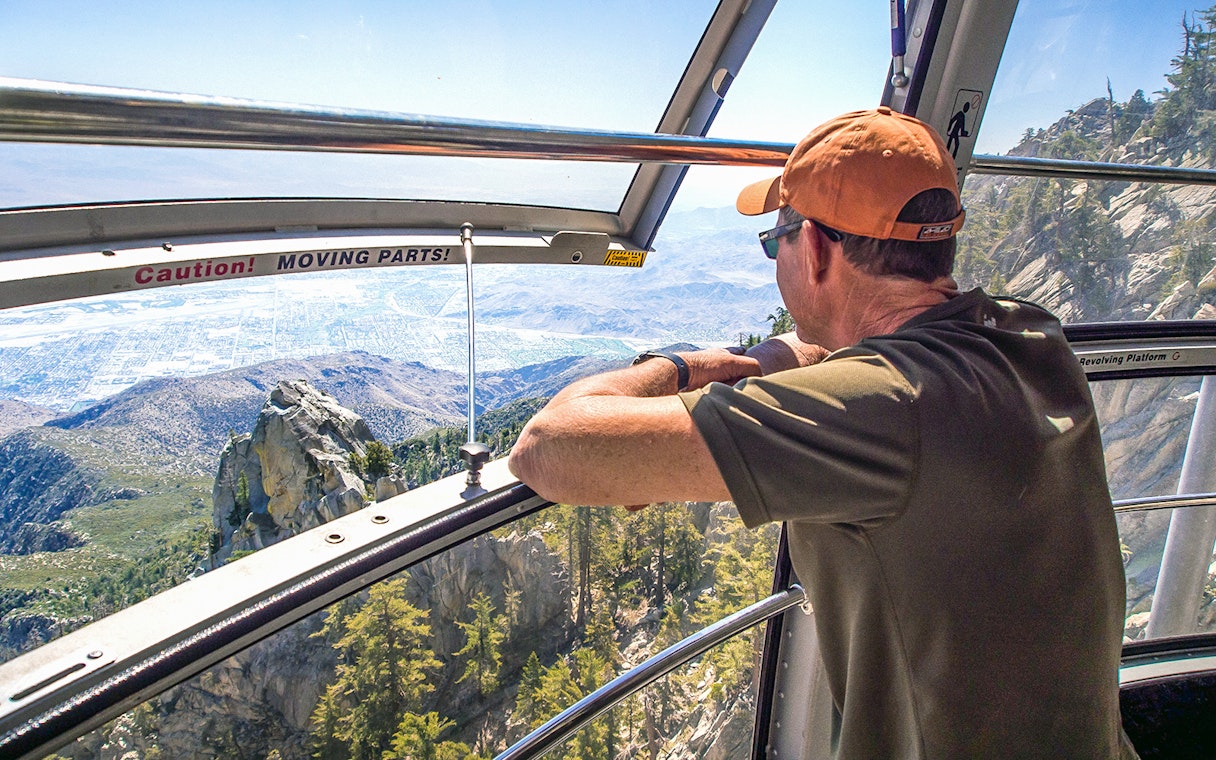 Man enjoying mountain view from Palm Springs Aerial Tramway cabin.
