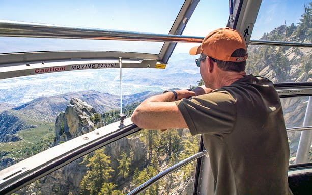 Man enjoying mountain view from Palm Springs Aerial Tramway cabin.