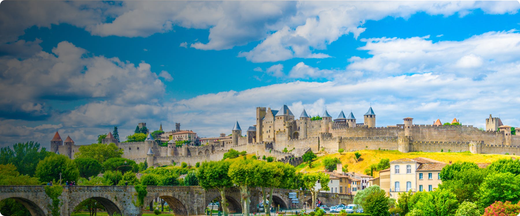 Medieval fortress of Carcassonne with stone bridge and lush greenery.