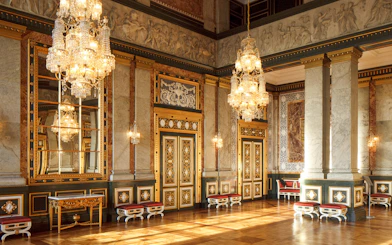 Interior of a grand hall in Copenhagen with ornate chandeliers and decorative walls.