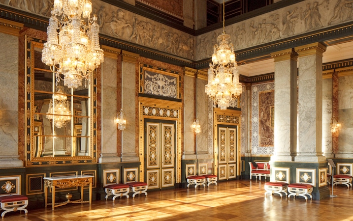 Interior of a grand hall in Copenhagen with ornate chandeliers and decorative walls.