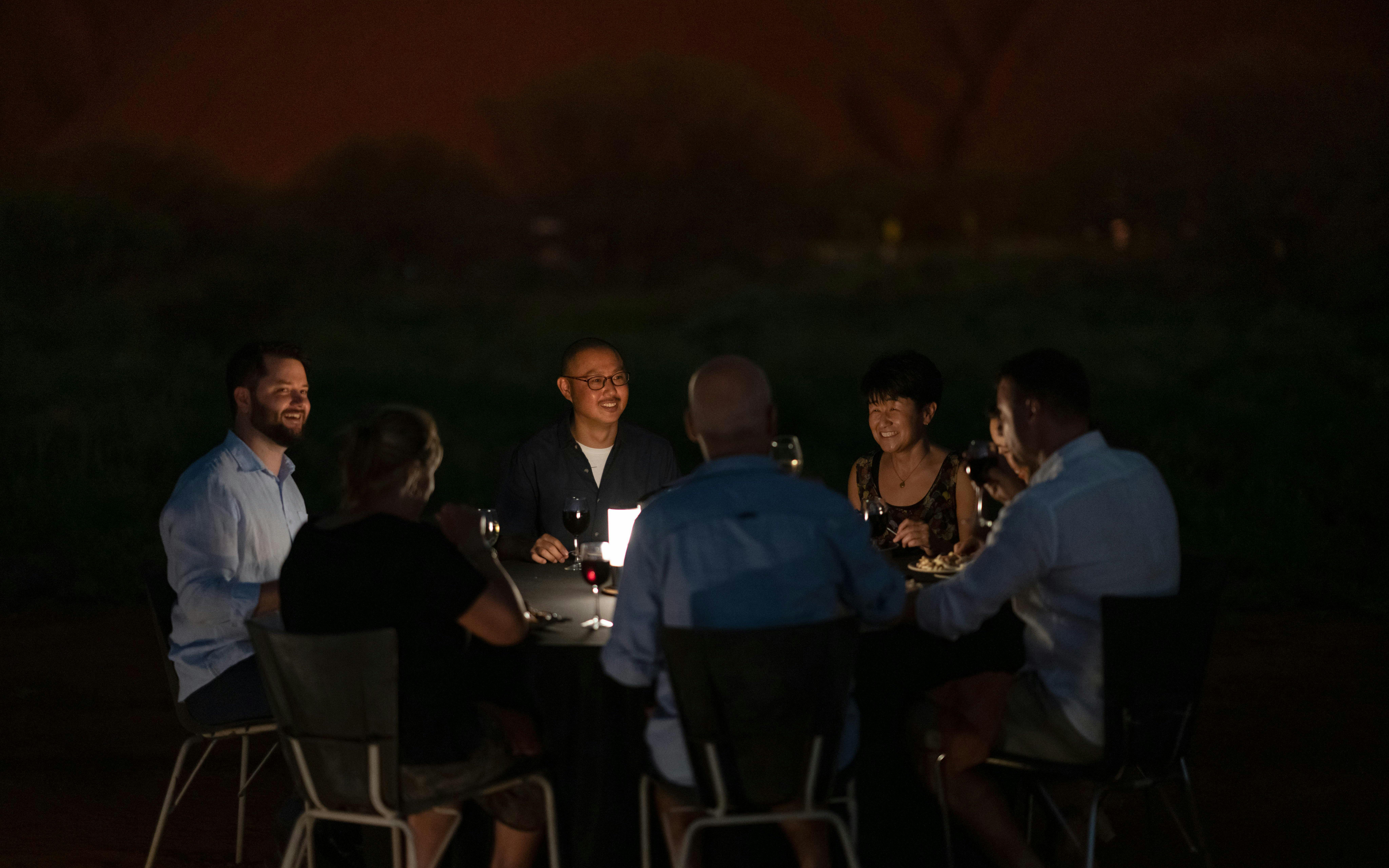 Group dining outdoors during Uluru sunset and stargazing tour with BBQ dinner.