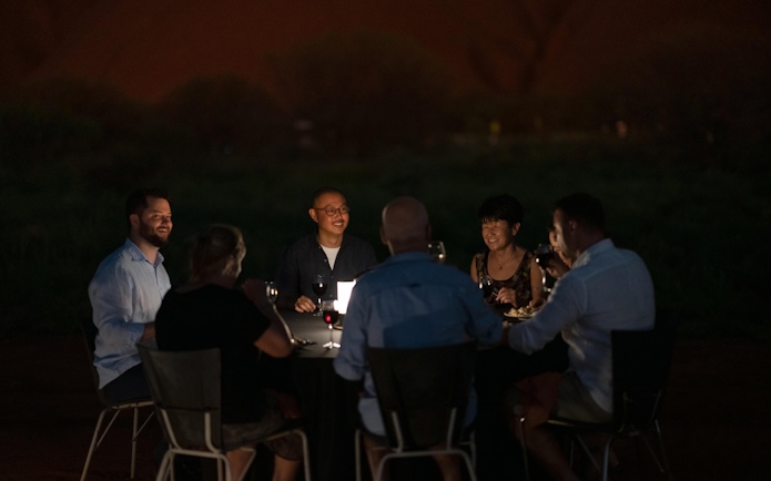 Group dining outdoors during Uluru sunset and stargazing tour with BBQ dinner.