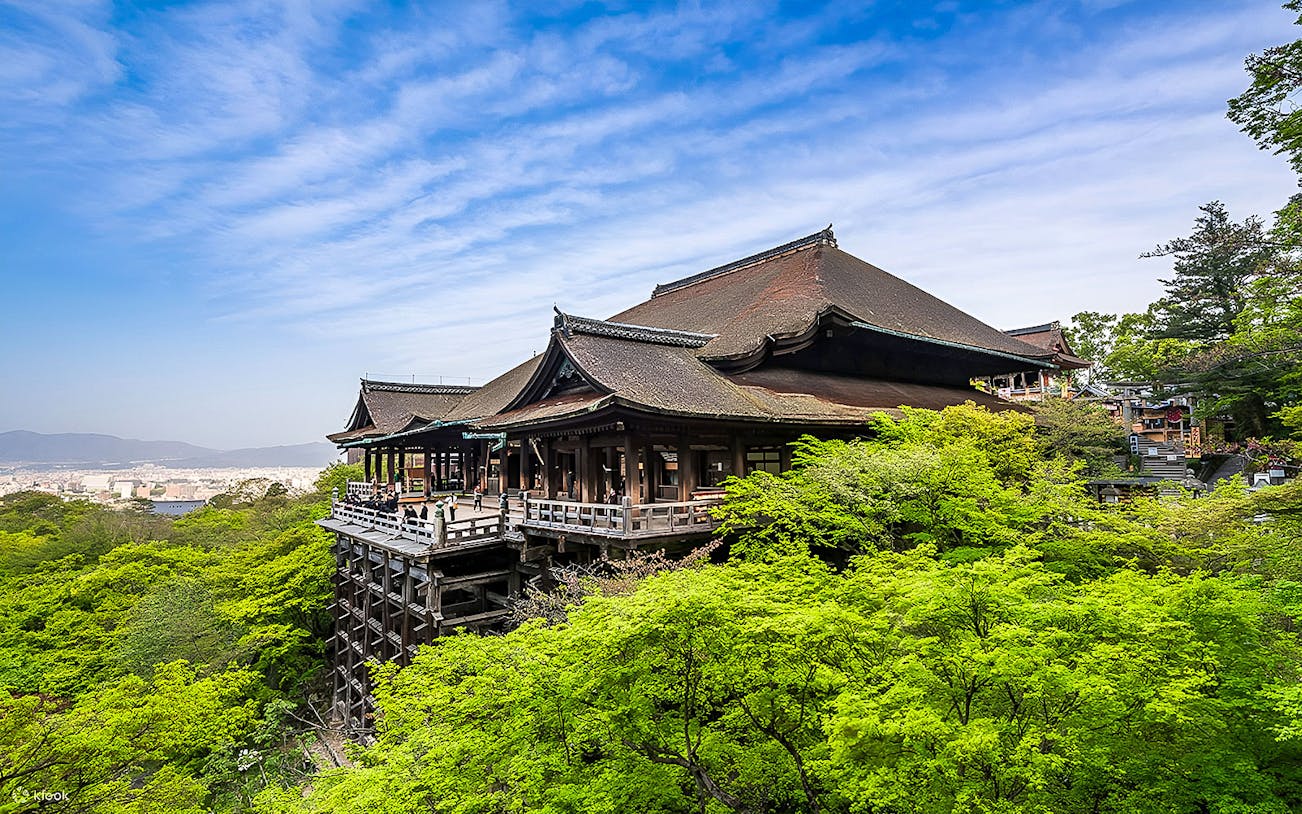 Kiyomizu-dera Temple in Kyoto surrounded by lush greenery under a clear blue sky.