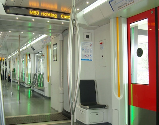 Amsterdam metro train arriving at a modern station platform with passengers boarding.