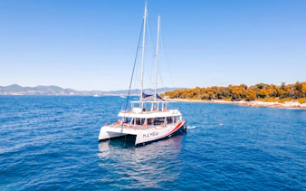 Catamaran sailing near Lérins Island, Marina Bay of Angels, with coastline view.