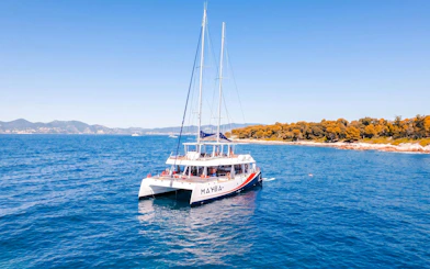 Catamaran sailing near Lérins Island, Marina Bay of Angels, with coastline view.