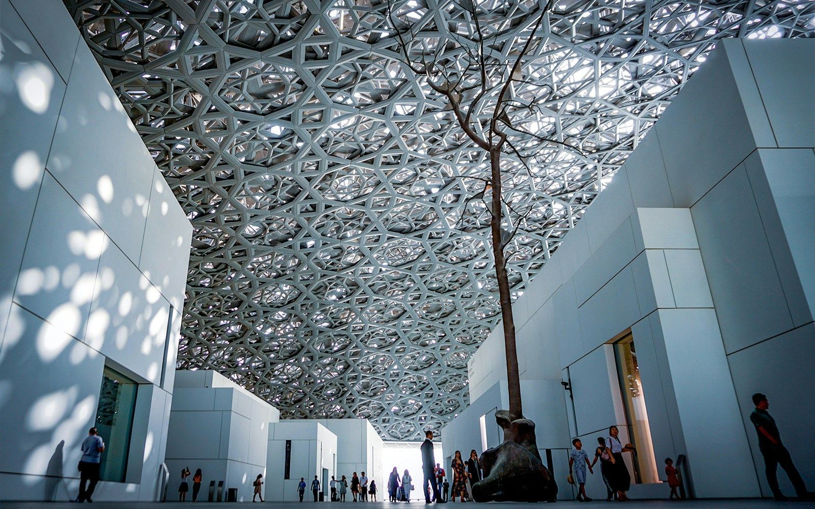 Louvre Abu Dhabi exterior with unique dome design and waterfront view.