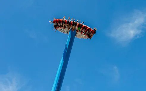 Visitors on a high-thrill ride at Vialand Theme Park, Istanbul against a clear blue sky.